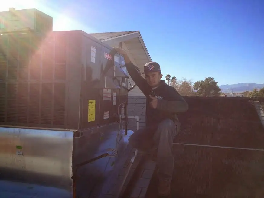 HVAC technician performing Air Duct Cleaning on a rooftop unit in Clay